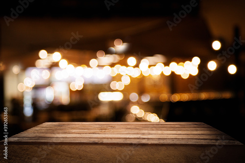 empty wooden table on blurred light gold bokeh of cafe restaurant on dark background