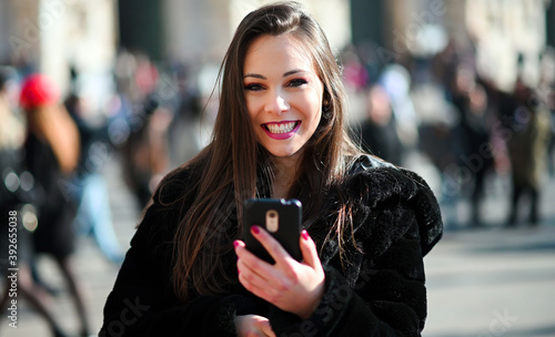 Beautiful young tourist girl in Milan using a smartphone