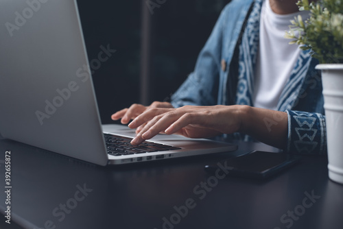 Casual woman hand typing on laptop computer overtime working at night at home office photo