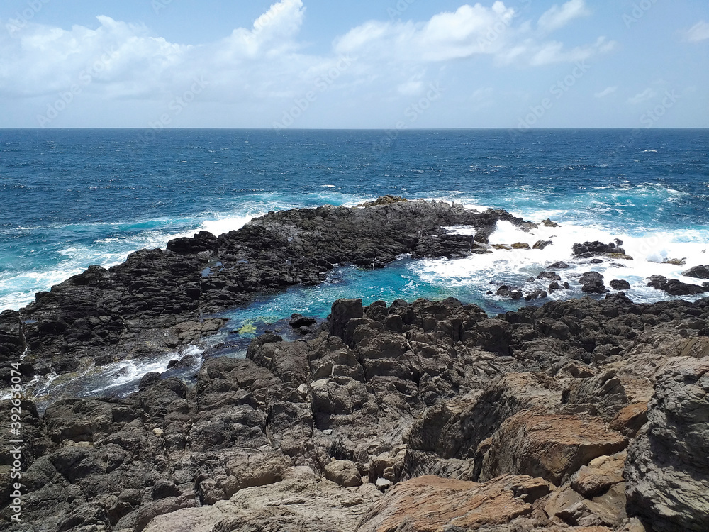Rocky Caribbean coastline with turquoise whitewater under tropical blue sky. Rocks carved by the tropical waters of FWI. Magical environment of wild nature background.