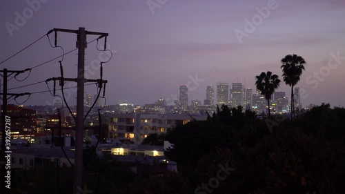 Beautiful purple California sky during sunset above downtown buildings and palm trees as planes fly over