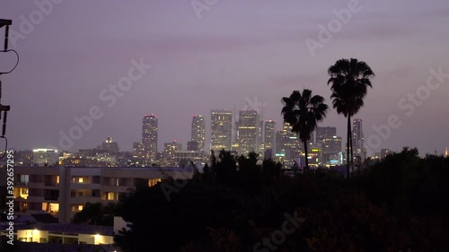Beautiful purple California sky during sunset above downtown buildings and palm trees as planes fly over