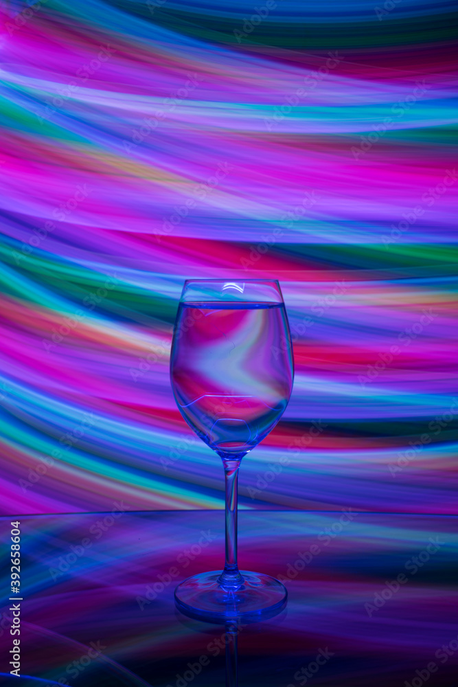 Light painting was done behind a glass filled with liquid and reflection of the glass on a reflective surface Light painting was done behind a glass filled with liquid and reflection of the glass on a reflective surface