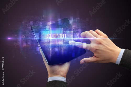 Businessman holding a foldable smartphone with SUPPORT inscription, new technology concept