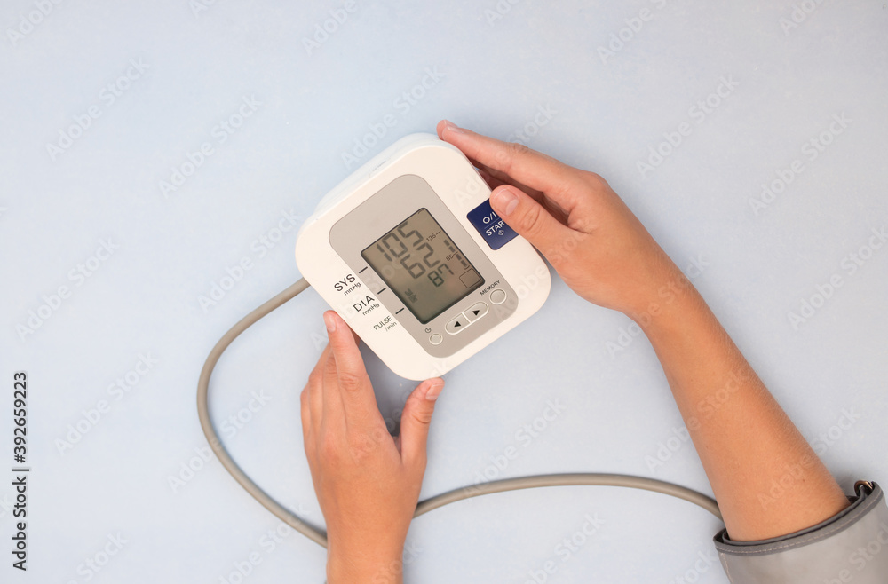 Measurement of pressure. A woman monitors her health by checking the pressure and pulse on her arm. View from above Measurement of pressure. A woman monitors her health by checking the pressure and pulse on her arm. View from above