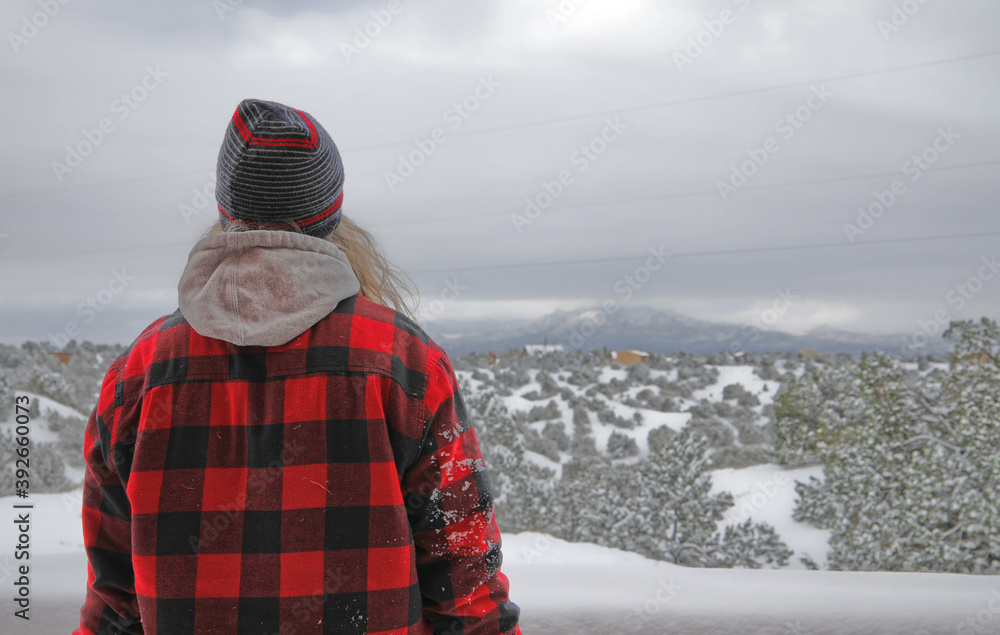 A man in the winter clothes  looking on a snowy southwest desert.