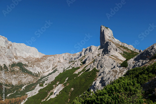 A view on a massive mountain wall in Alps in Hochschwab region, Austria. The slopes are really steep and dangerous to climb. Rocky landscape. Golden grass, autumn vibes. Freedom and wilderness