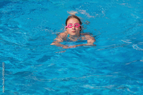 Girl in glasses swim in the blue swimming pool. © idea_studio
