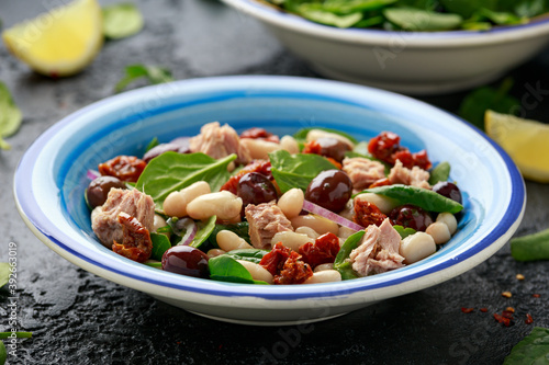 Tuna, white bean salad with olive, red onion, spinach and dried tomato. Healthy food.
