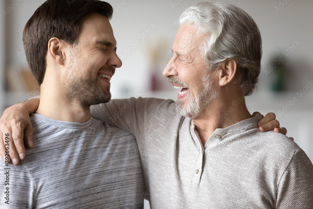 Close up overjoyed mature father with son laughing, excited older grandfather and grown up grandchild having fun, hugging and chatting, enjoying leisure time together, two generations bonding Close up overjoyed mature father with son laughing, excited older grandfather and grown up grandchild having fun, hugging and chatting, enjoying leisure time together, two generations bonding