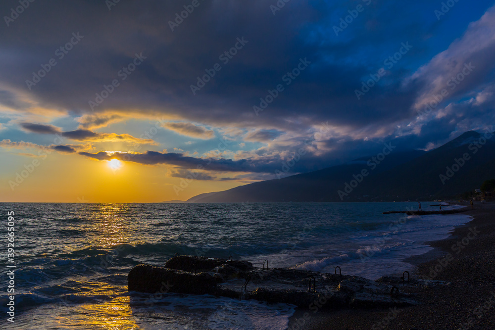 Fototapeta premium Beautiful shoreline scene with waves at sunset beams