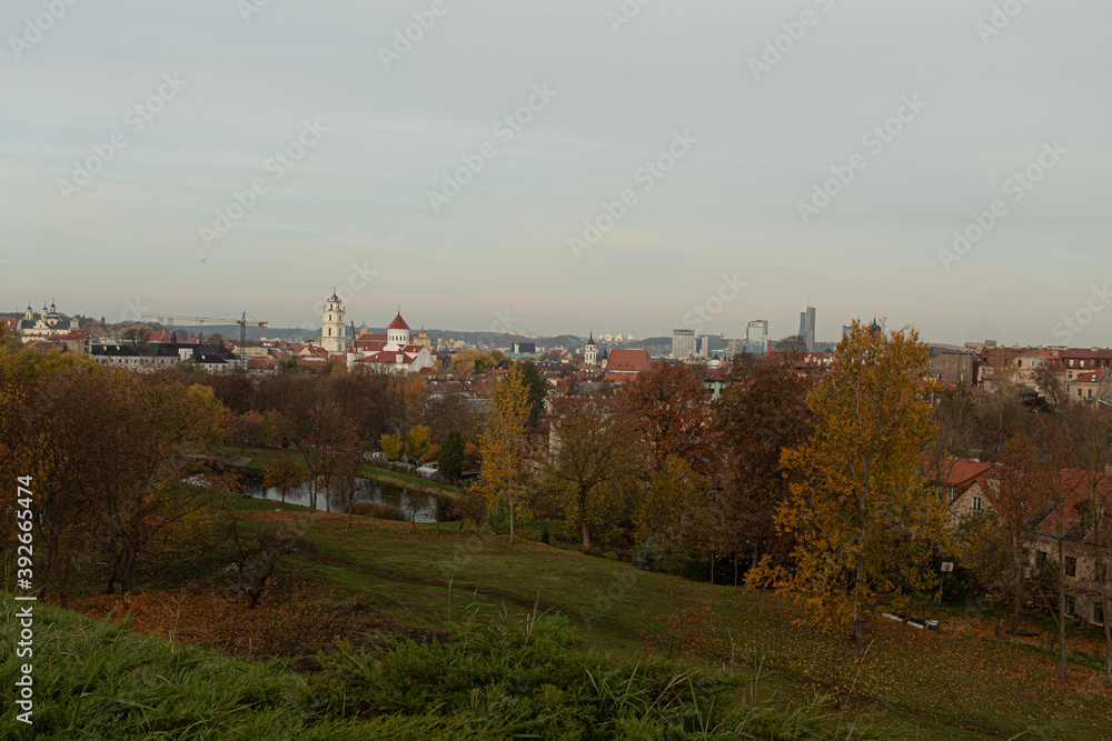Fototapeta premium Panoramic photo of Vilnius old town, peach rooftops and golden trees during the fall season. Vilnius historic centre was declared Unesco heritage in 1994.