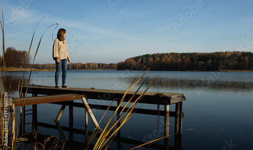 Attractive young female standing on top of a pier while witnessing the Galve lake in Trakai, Lithuania. Trakai was the ancient capital of this baltic republic.