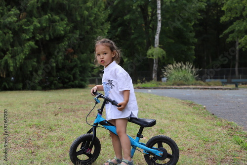 Fille 3 ans mix franco chinois fait du vélo dans un parc