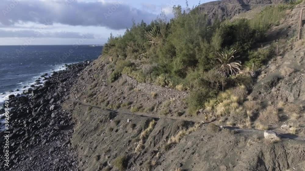 Single Trail Jogger On Hard Rough Rocky Coast Path, Tracking Drone Shot Single Trail Jogger On Hard Rough Rocky Coast Path, Tracking Drone Shot