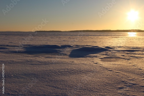 A orange sky and a reflex on the snow of a frozen lake from a setting sun as a natural background or texture