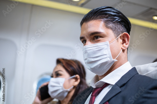 Portrait of business man and woman in medical face mask sitting at seat in airplane cabin. business airline protection for Covid-19. new normal travel abroad concept