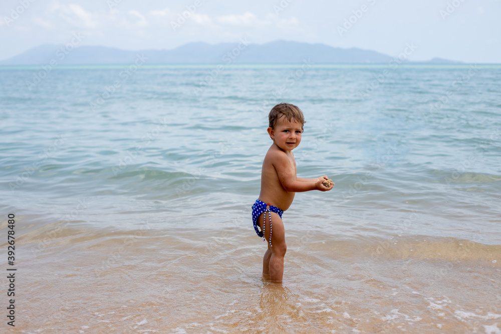 adorable toddler toddler has fun playing on sandy beach of tropical sea