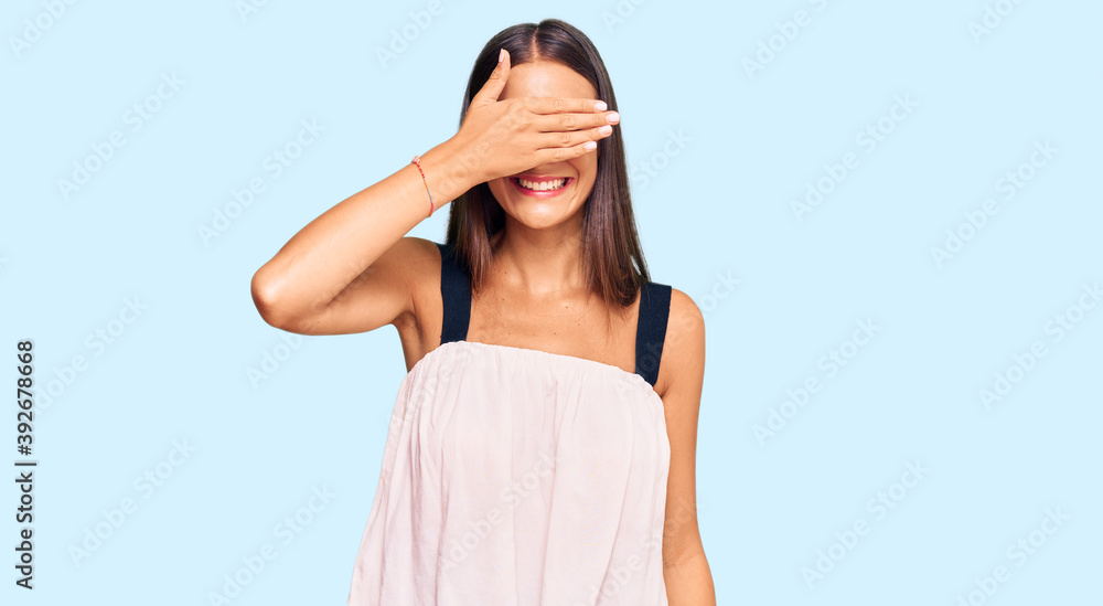Young hispanic woman wearing casual clothes smiling and laughing with hand on face covering eyes for surprise. blind concept. Young hispanic woman wearing casual clothes smiling and laughing with hand on face covering eyes for surprise. blind concept.