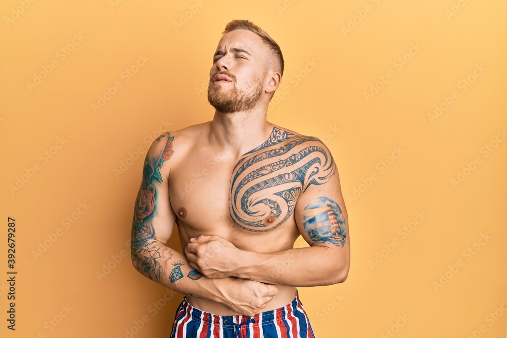 Young caucasian man wearing swimwear shirtless with hand on stomach because nausea, painful disease feeling unwell. ache concept.