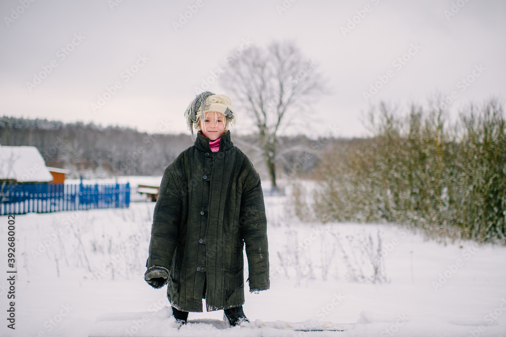 Emotional portrait of positive slavonic girl wearing loose fit padded jacket with scarf on her head in winter snowy day in village Emotional portrait of positive slavonic girl wearing loose fit padded jacket with scarf on her head in winter snowy day in village