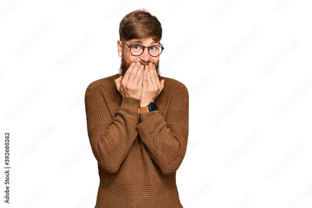 Young irish redhead man wearing casual clothes and glasses laughing and embarrassed giggle covering mouth with hands, gossip and scandal concept Young irish redhead man wearing casual clothes and glasses laughing and embarrassed giggle covering mouth with hands, gossip and scandal concept