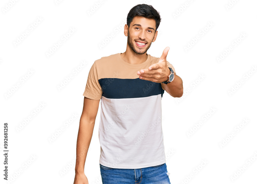 Young handsome man wearing casual clothes smiling cheerful offering palm hand giving assistance and acceptance. Young handsome man wearing casual clothes smiling cheerful offering palm hand giving assistance and acceptance.