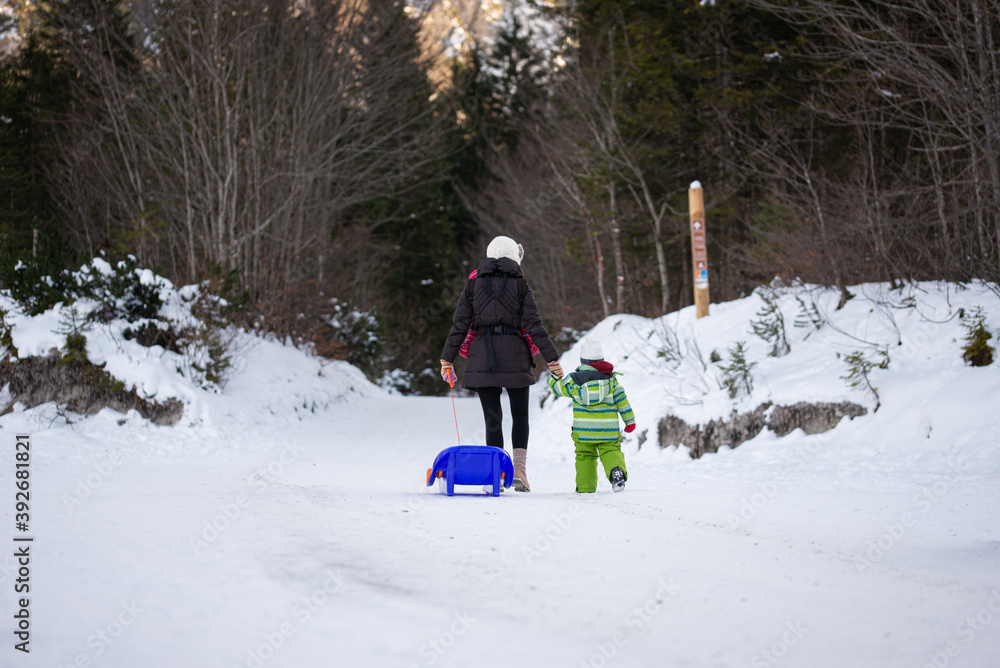 Mother walking in snowy nature with her toddler child