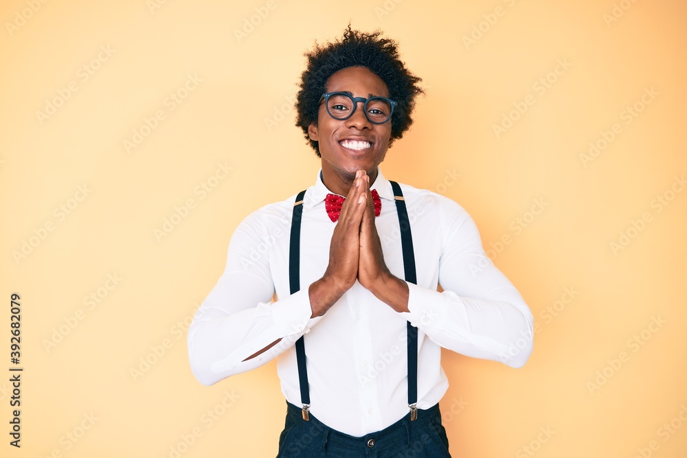 Handsome african american man with afro hair wearing hipster elegant look praying with hands together asking for forgiveness smiling confident. Handsome african american man with afro hair wearing hipster elegant look praying with hands together asking for forgiveness smiling confident.