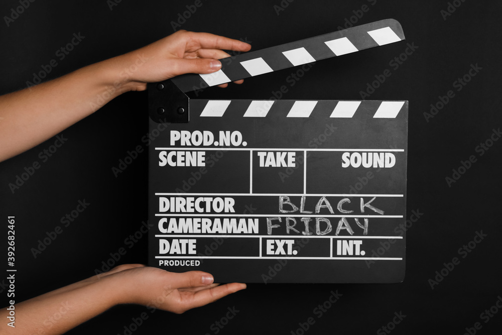 Woman with clapperboard against dark background, closeup. Black Friday concept
