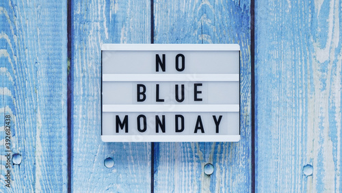 Blue monday day banner concept. White board with text no blue monday on blue wooden background, top view, flat lay. photo