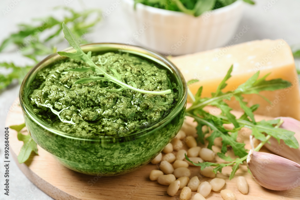 Bowl of tasty arugula pesto and ingredients on table Bowl of tasty arugula pesto and ingredients on table