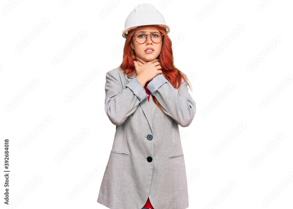 Young redhead woman wearing architect hardhat shouting and suffocate because painful strangle. health problem. asphyxiate and suicide concept. Young redhead woman wearing architect hardhat shouting and suffocate because painful strangle. health problem. asphyxiate and suicide concept.
