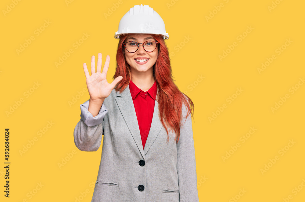 Young redhead woman wearing architect hardhat showing and pointing up with fingers number five while smiling confident and happy. Young redhead woman wearing architect hardhat showing and pointing up with fingers number five while smiling confident and happy.