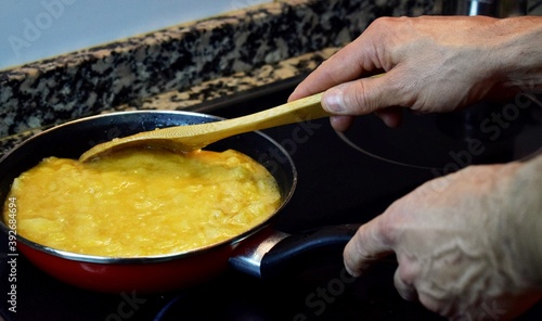hombre cocinando, terminando una tortilla de patata española