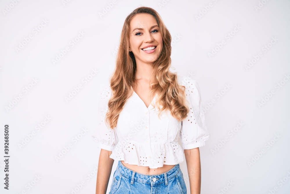 Young caucasian woman with blond hair wearing casual summer clothes looking positive and happy standing and smiling with a confident smile showing teeth Young caucasian woman with blond hair wearing casual summer clothes looking positive and happy standing and smiling with a confident smile showing teeth