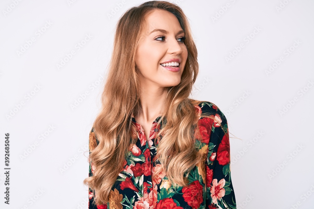 Young caucasian woman with blond hair wearing elegant floral shirt looking to side, relax profile pose with natural face and confident smile. Young caucasian woman with blond hair wearing elegant floral shirt looking to side, relax profile pose with natural face and confident smile.
