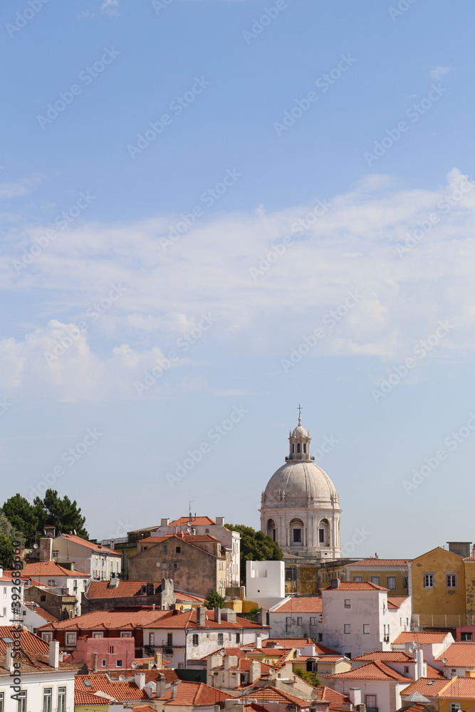 Vertical shot of the city of Lisbon, Portugal with a dome tower of a church under blue sky