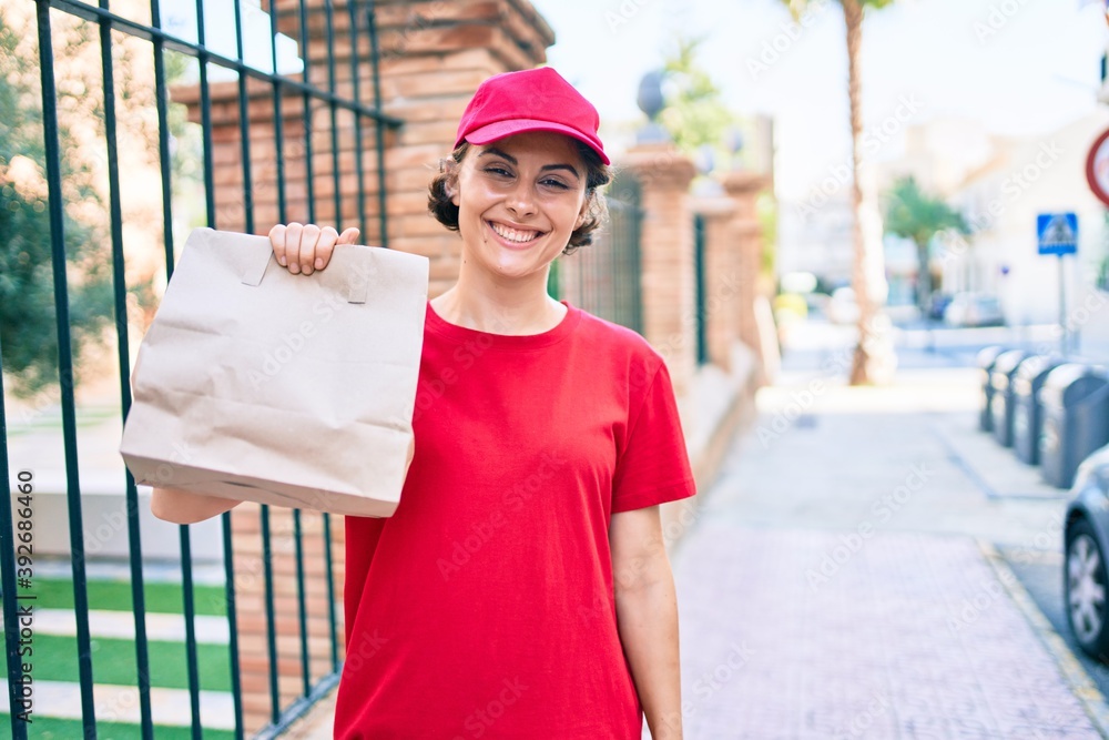 Delivery business worker woman wearing uniform smiling happy holding paper bag