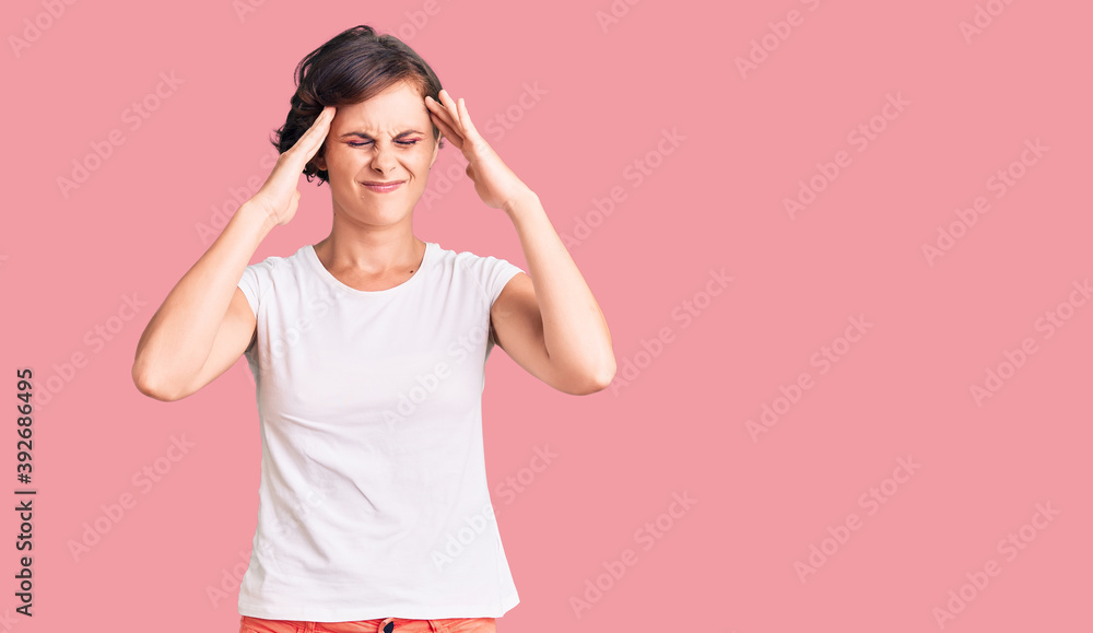 Beautiful young woman with short hair wearing casual clothes suffering from headache desperate and stressed because pain and migraine. hands on head. Beautiful young woman with short hair wearing casual clothes suffering from headache desperate and stressed because pain and migraine. hands on head.