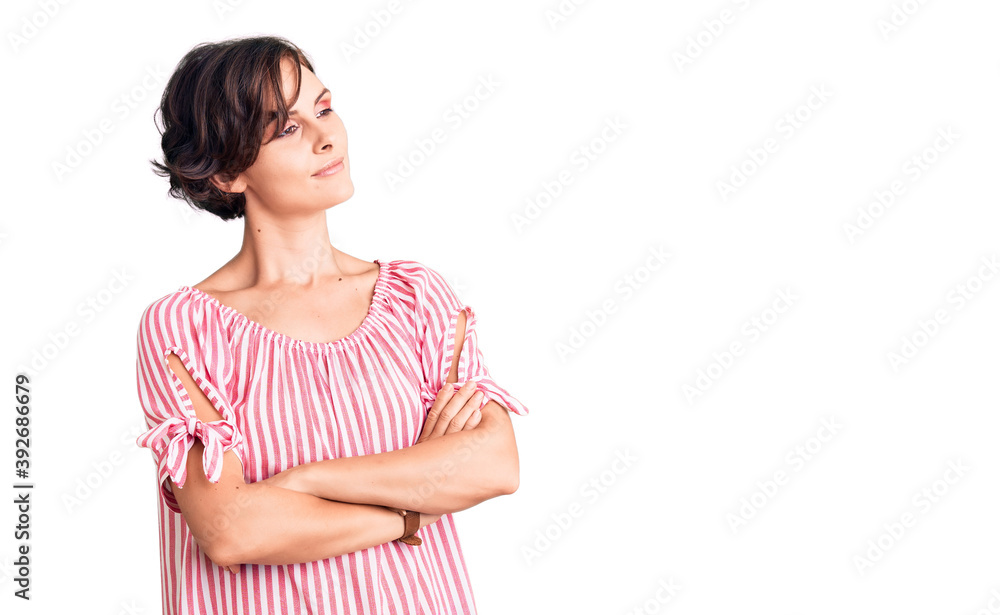 Beautiful young woman with short hair wearing casual summer clothes looking to the side with arms crossed convinced and confident Beautiful young woman with short hair wearing casual summer clothes looking to the side with arms crossed convinced and confident