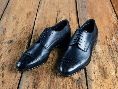 Men's classic black leather shoes lie on old boards side view