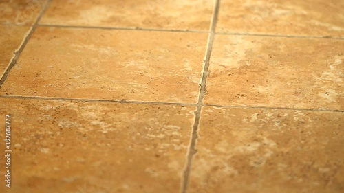 Cinematic prospective 4k shot of bathroom tile floor. Flooring tiles are made of ceramic in yellowish colors. photo