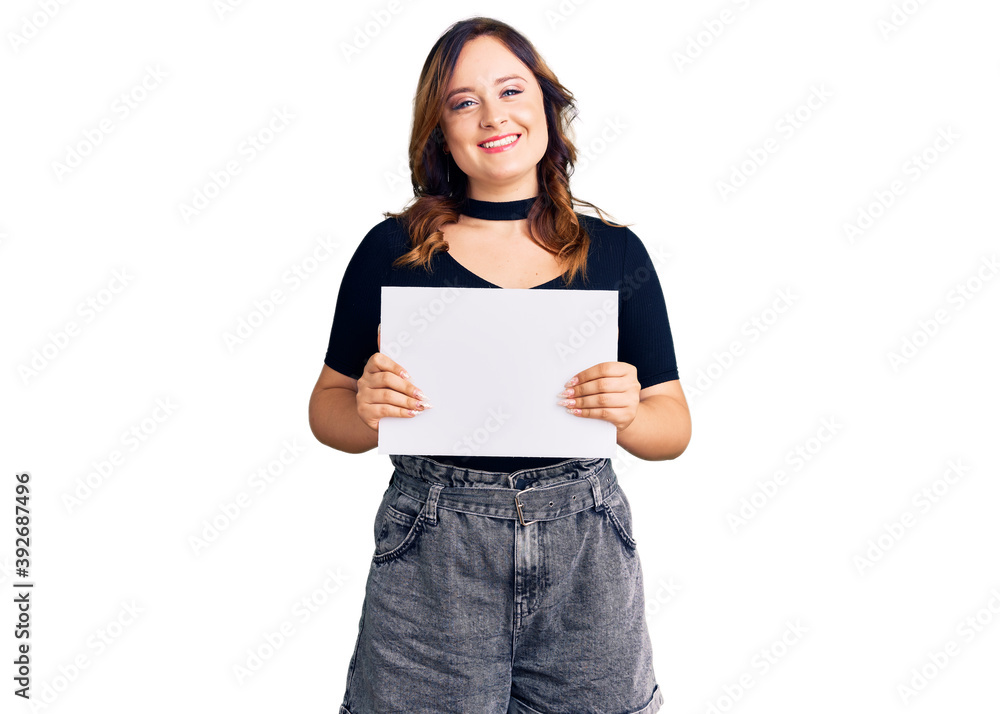 Young beautiful caucasian woman holding blank empty paper looking positive and happy standing and smiling with a confident smile showing teeth Young beautiful caucasian woman holding blank empty paper looking positive and happy standing and smiling with a confident smile showing teeth