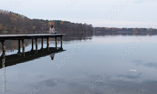 Attractive young female sitting at the edge of a pier while enjoying the views of a lake in Trakai, Lithuania. This city was the ancient capital of this baltic republic.