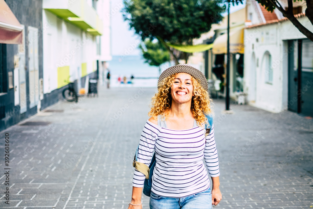portrait of young beautiful curly woman looking at the camera while walking in the street discovering and traveling new places