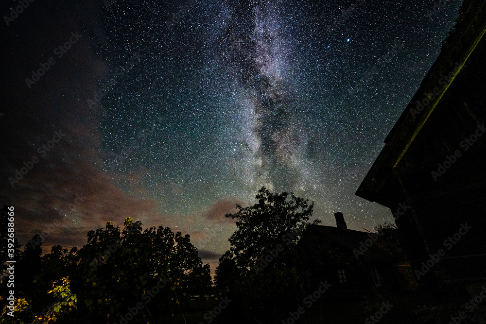 Overhead milky way with stars in clear summer night. Old barn house. Country side.