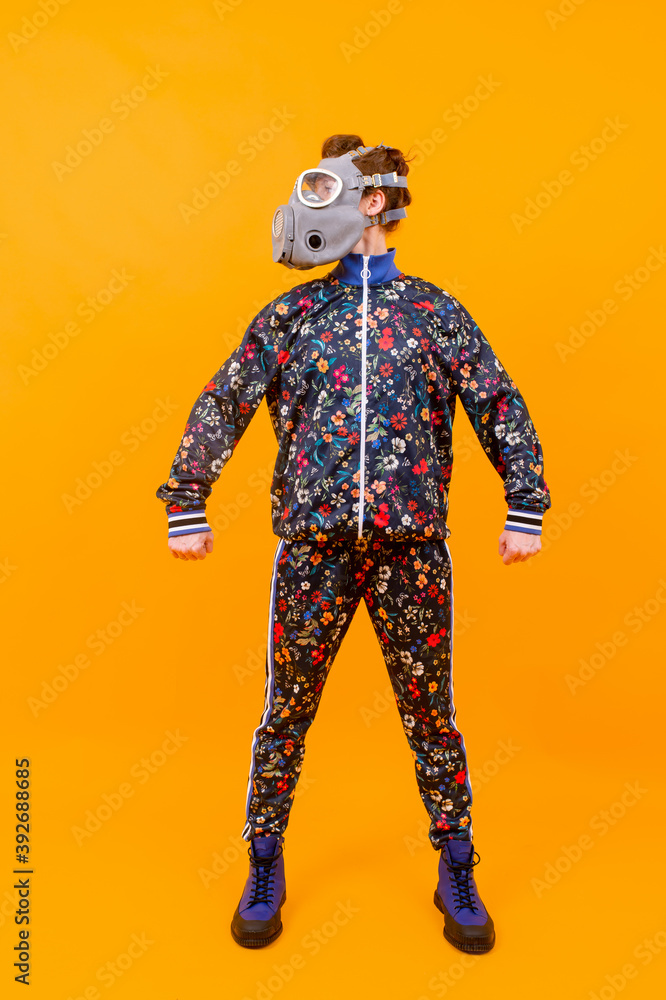 Stylish strange woman in respirator posing over orange background Stylish strange woman in respirator posing over orange background