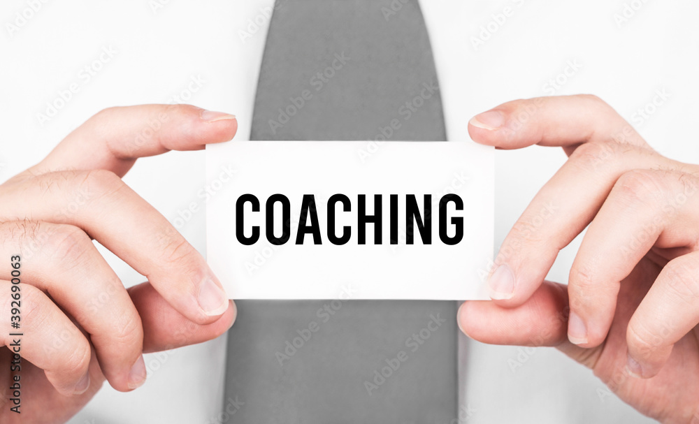 Businessman holding a card with text Coaching,business concept Businessman holding a card with text Coaching,business concept