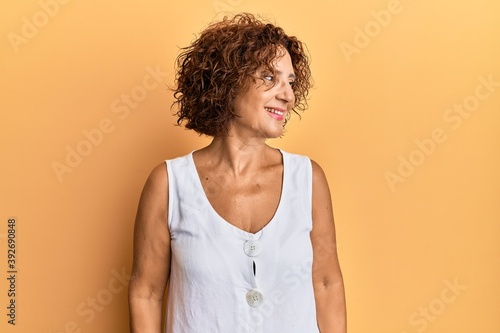 Beautiful middle age mature woman wearing casual clothes looking away to side with smile on face, natural expression. laughing confident.